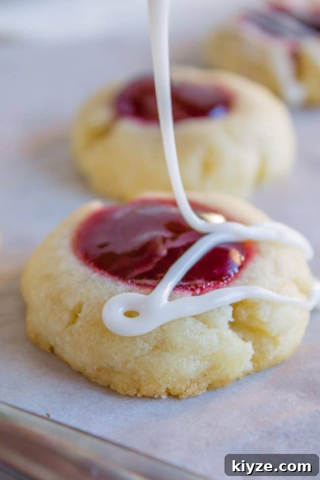 Almond Raspberry Thumbprint Cookies: Chewy Jam-Filled Recipe 13 Drizzling glaze on a thumbprint cookie.