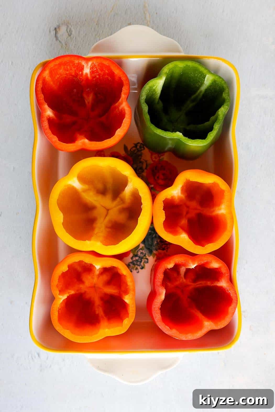 Ground Turkey and Rice Stuffed Bell Peppers Recipe 4 Six bell peppers green, red, yellow, and orange with the tops cut off and seeds removed standing upright in a small baking dish.