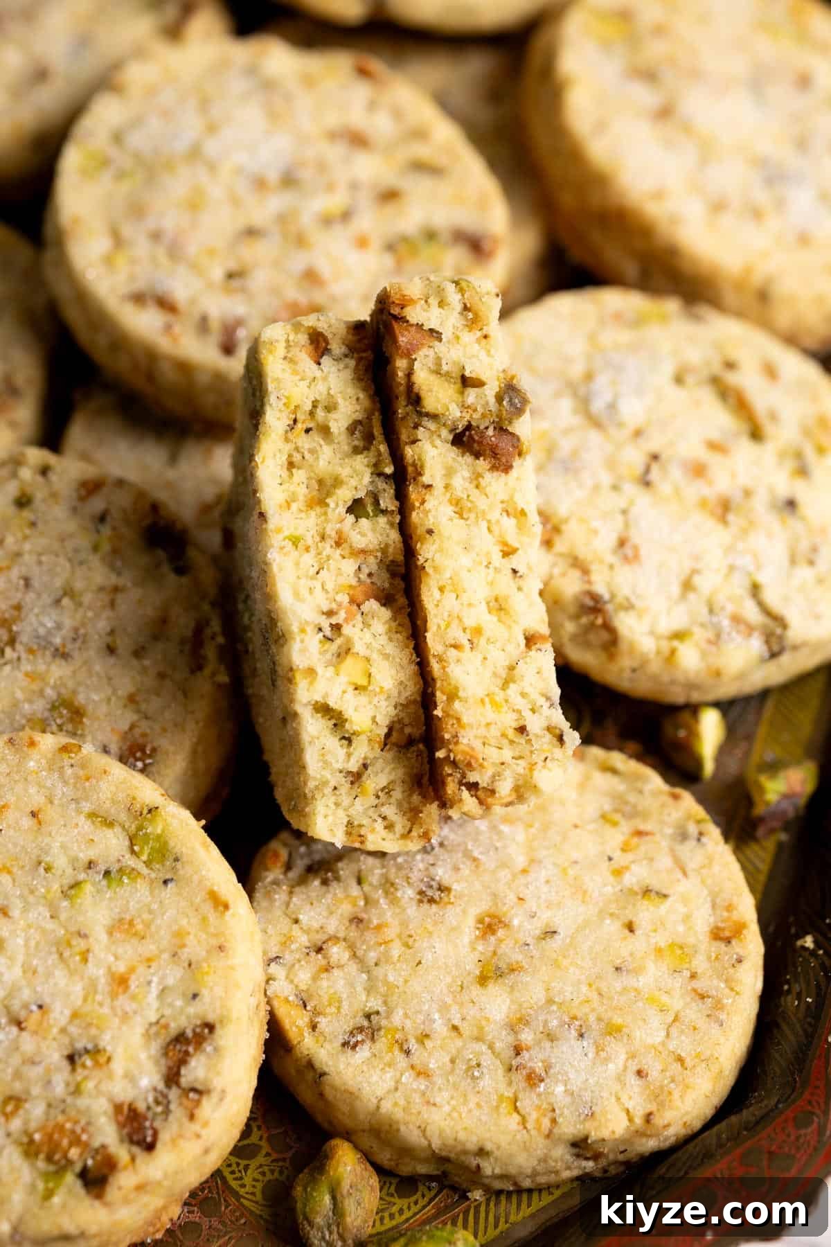 A pistachio cookie broken in halves to show the interior texture.