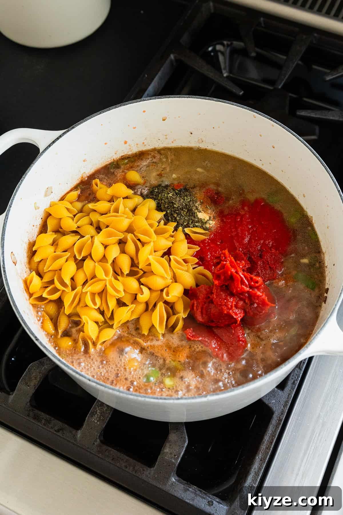 Classic American Chop Suey with Ground Beef Recipe 5 Adding sauces and dry pasta to the cooking pot.