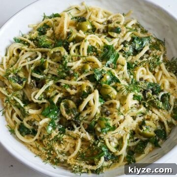Pasta with Green Olives, Capers & Fresh Herbs Recipe 7 Linguine pasta with green olives, herbs, and capers topped with bread crumbs in a white bowl sitting on a white surface.