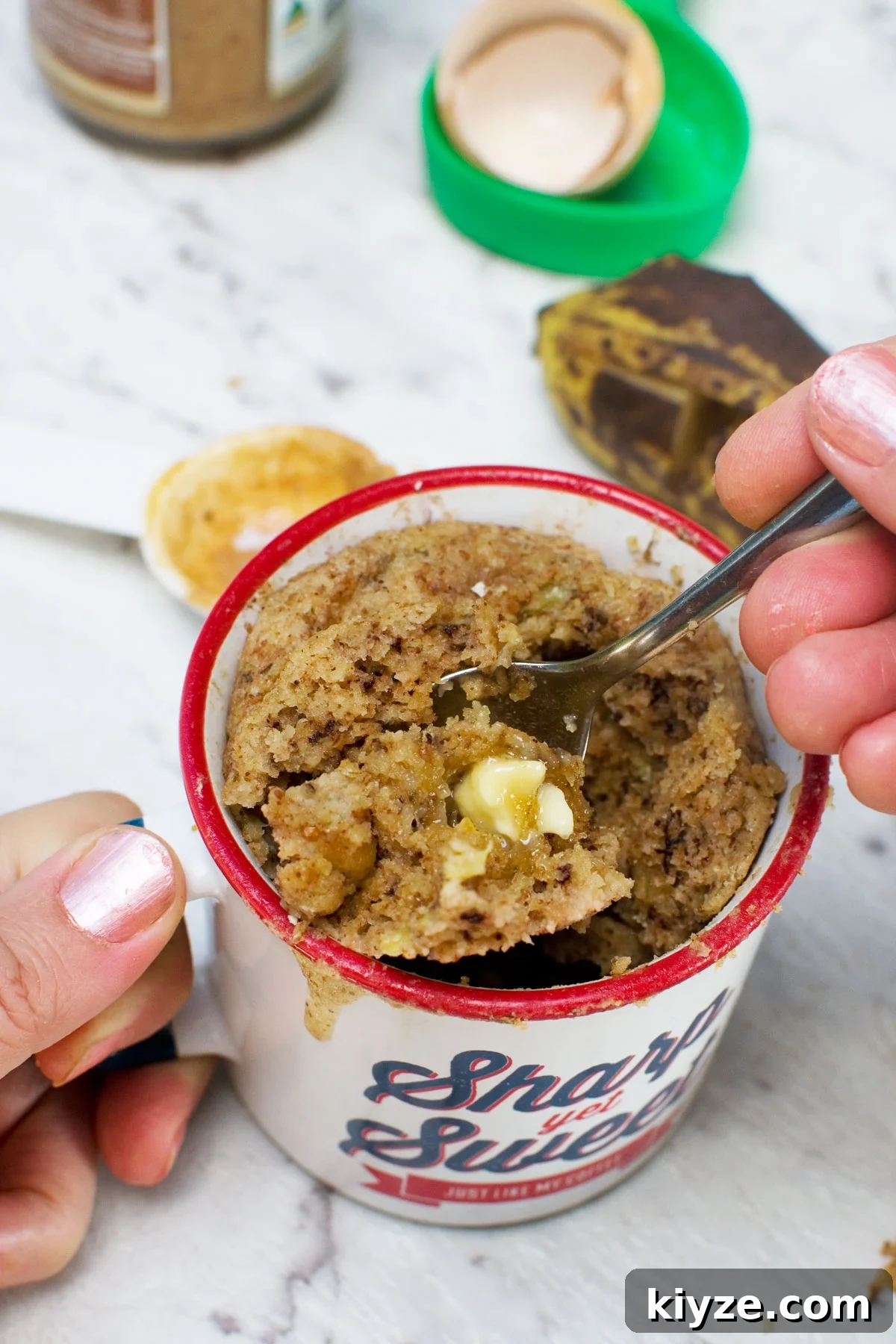 Gluten-Free Banana Mug Cake Recipe — Quick Single-Serve Dessert 2 someone eating a gluten free banana mug cake with a spoon - various ingredients are scattered around