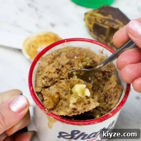 Gluten-Free Banana Mug Cake Recipe — Quick Single-Serve Dessert 6 Someone eating a gluten free mug cake with banana, almond and white chocolate