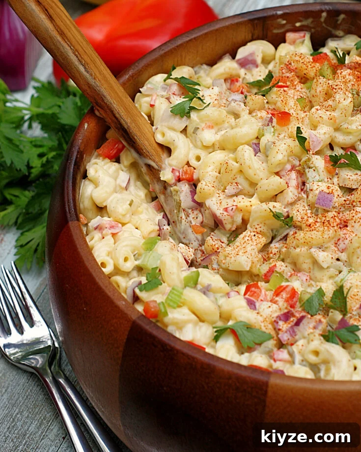 A bowl of southern macaroni salad loaded with red onion, red bell pepper, celery, boiled eggs and elbow macaroni.