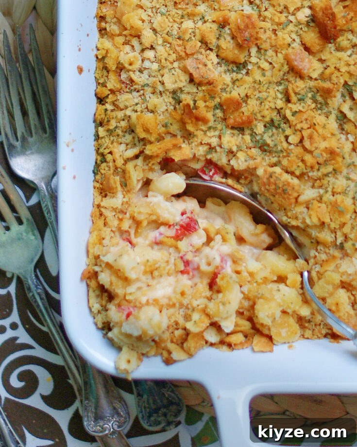 A casserole dish of baked macaroni and cheese made with pimento cheese and a ritz cracker crust.