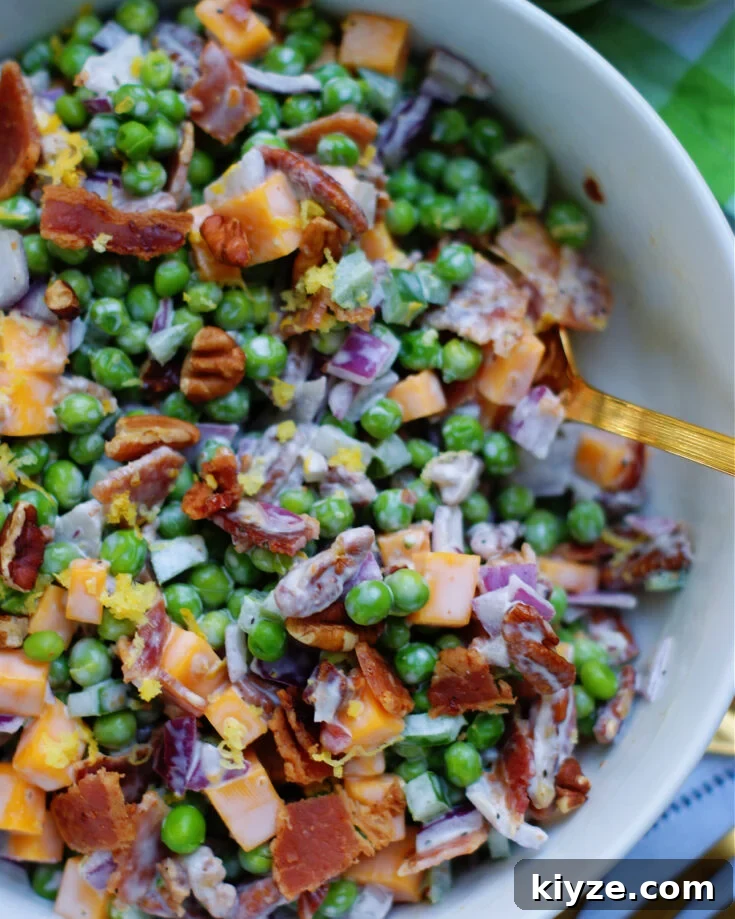 Upclose of green pea salad to size and texture of cheese, red onion, bacon, chopped pecans and lemon zest.