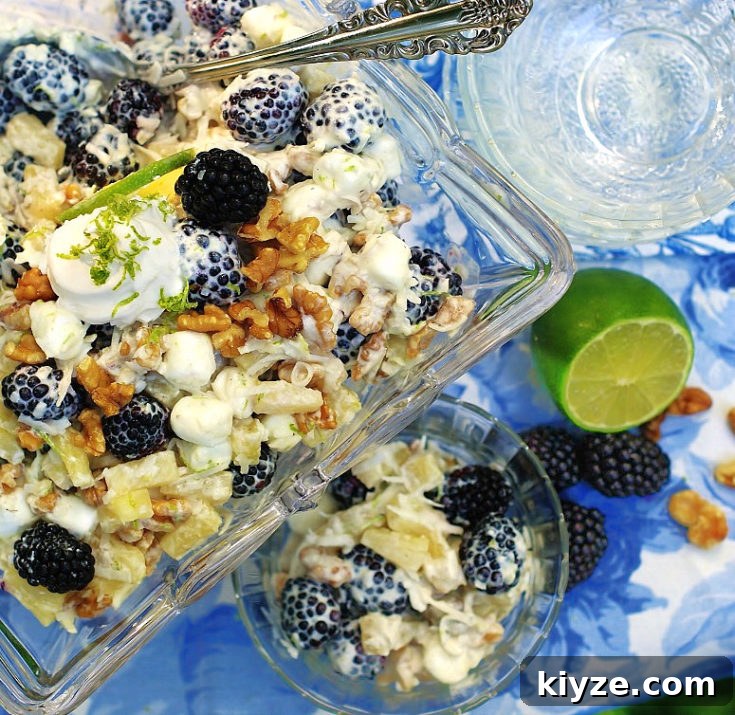 Easy summer ambrosia with a tropical flair. Filled with coconut, pineapple, blackberries and lime all swathed in clouds of cool whip, lime yogurt and mini marshmallows.
