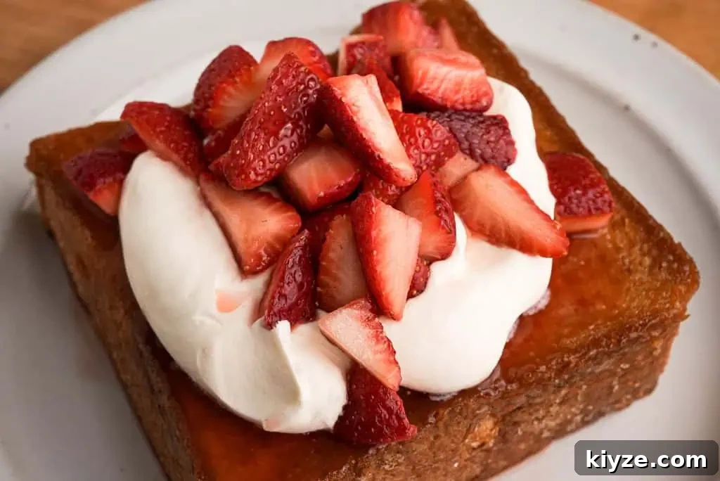 honey butter toast topped with rose whipped cream and strawberries on a plate
