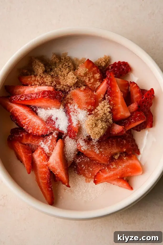 a bowl of quartered strawberries topped with brown and white sugar