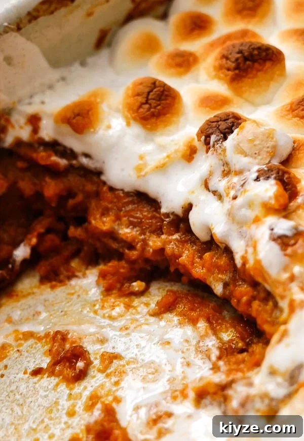 A closeup of sweet potato casserole with marshmallows in a baking dish. 