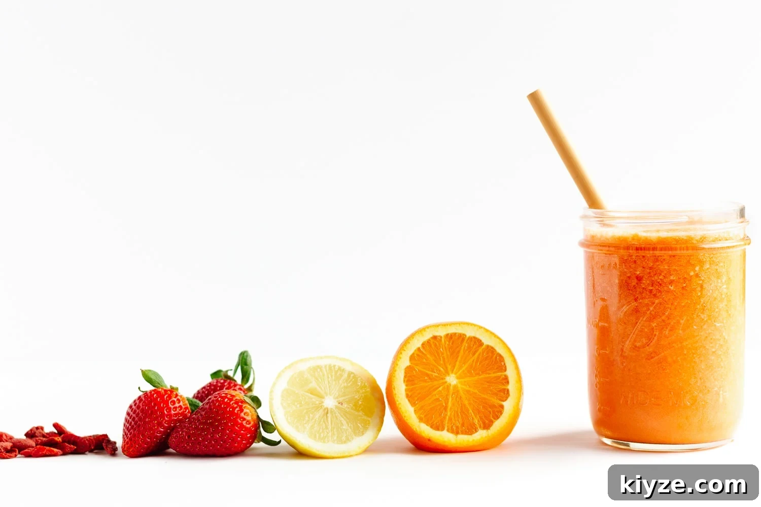 High-Vitamin C Immunity-Boost Smoothie Recipe 3 Goji berries, strawberries, lemon, orange and glass of Vitamin C Smoothie lined up on a white background.