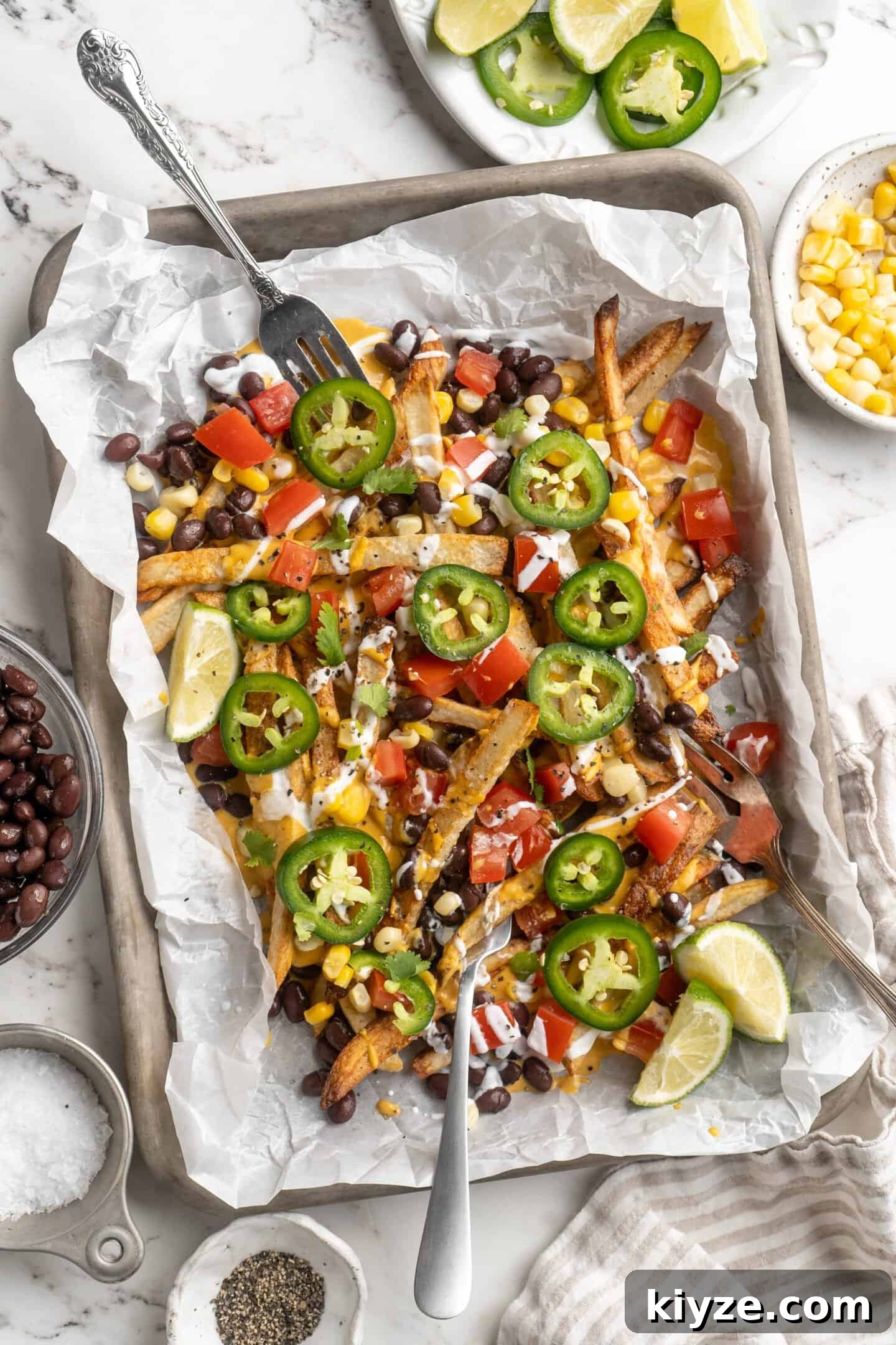 Get the party started with loaded nacho fries! They're topped with all your favourite nacho toppings to create an irresistible appetizer. Overhead view of loaded nacho fries on sheet pan with forks