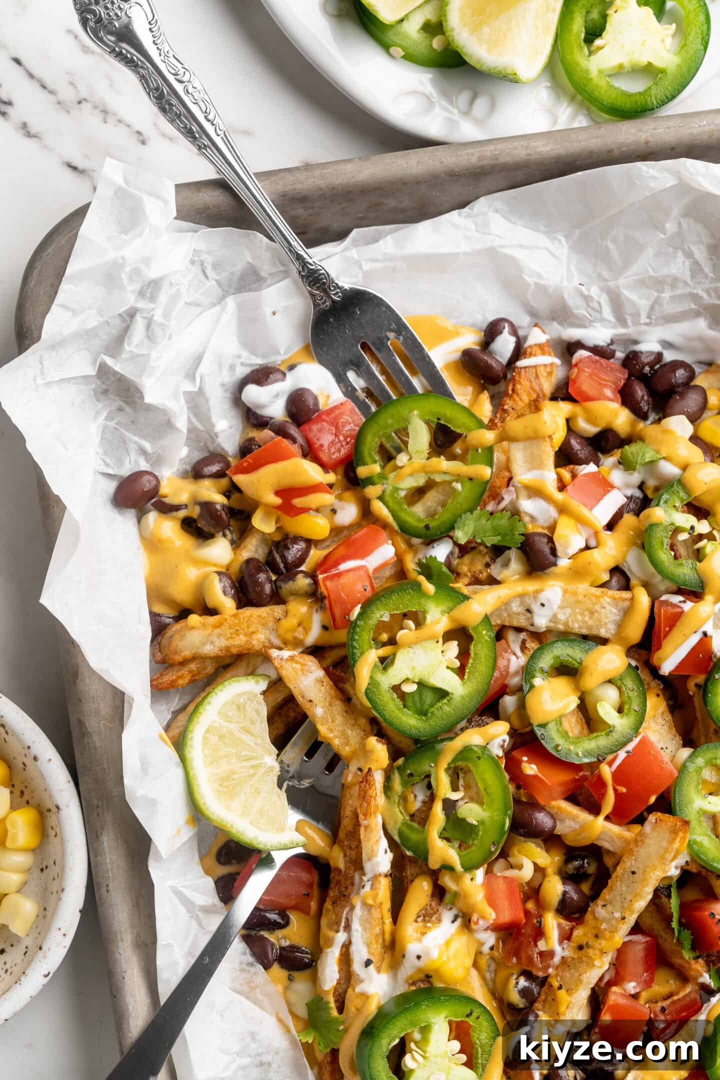 Get the party started with loaded nacho fries! They're topped with all your favourite nacho toppings to create an irresistible appetizer. Sheet pan with loaded nacho fries, with forks digging in