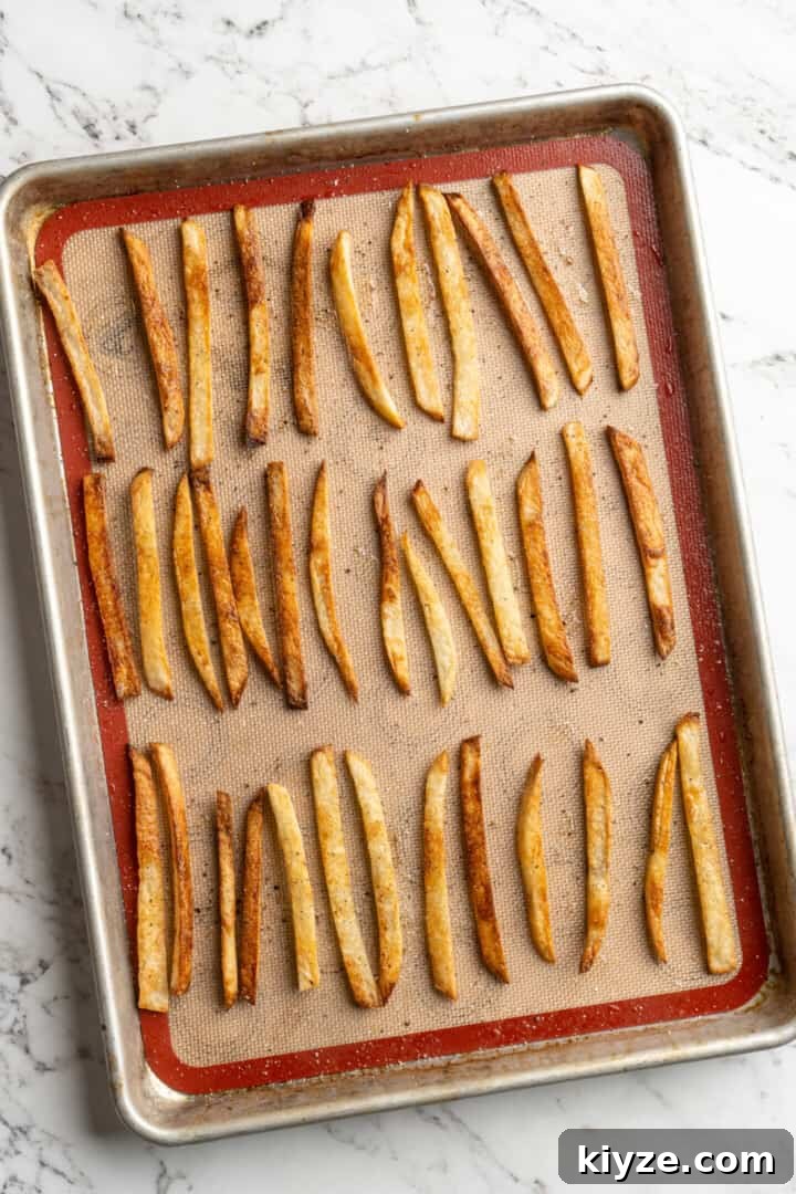 Get the party started with loaded nacho fries! They're topped with all your favourite nacho toppings to create an irresistible appetizer. Overhead view of homemade fries on sheet pan