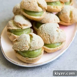 Matcha Cream Puffs Recipe: Light Japanese Green Tea Choux Pastry 13 Matcha Cream Puffs arranged on pink serving plate.