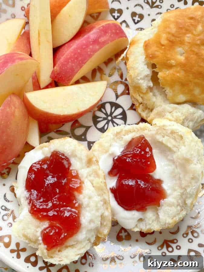 Air Fryer Guide: Crispy Frozen Grands Biscuits in Minutes 2 a plate of two cooked biscuits, buttered and with jam with a side of sliced apples