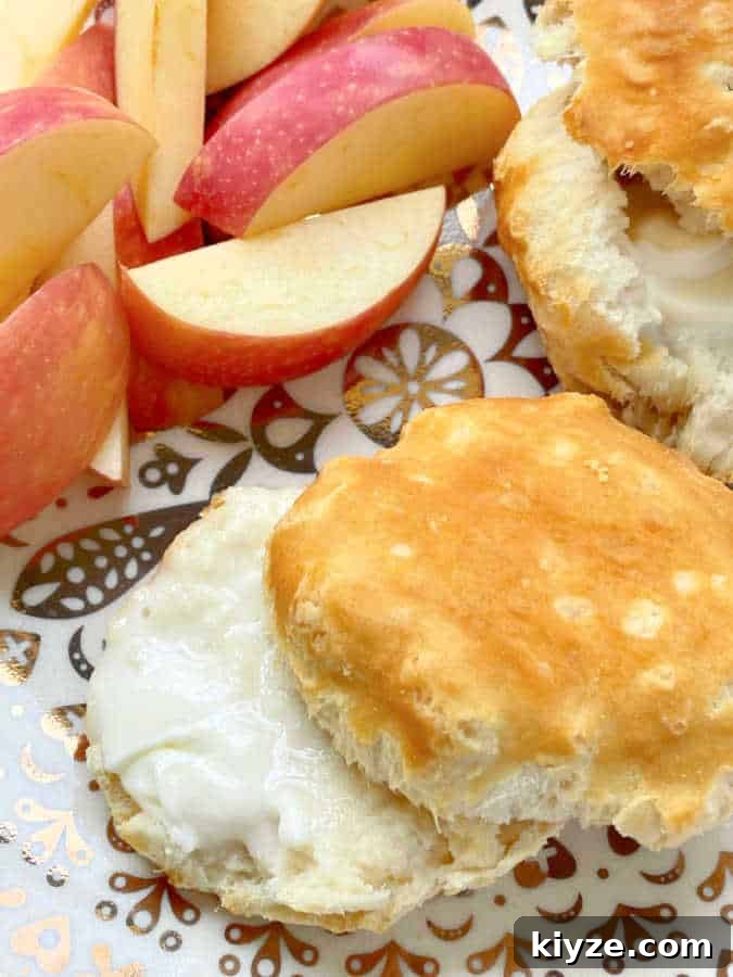 Air Fryer Guide: Crispy Frozen Grands Biscuits in Minutes 5 two buttered biscuits that have been cooked in the air fryer, plated with fresh sliced apples