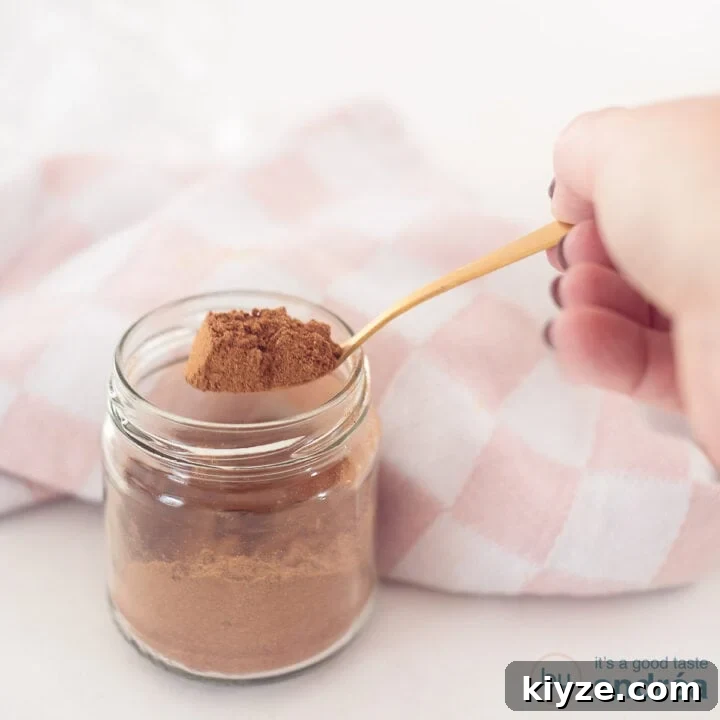 A square photo with a glass jar with a spoon showing gingerbread spices.