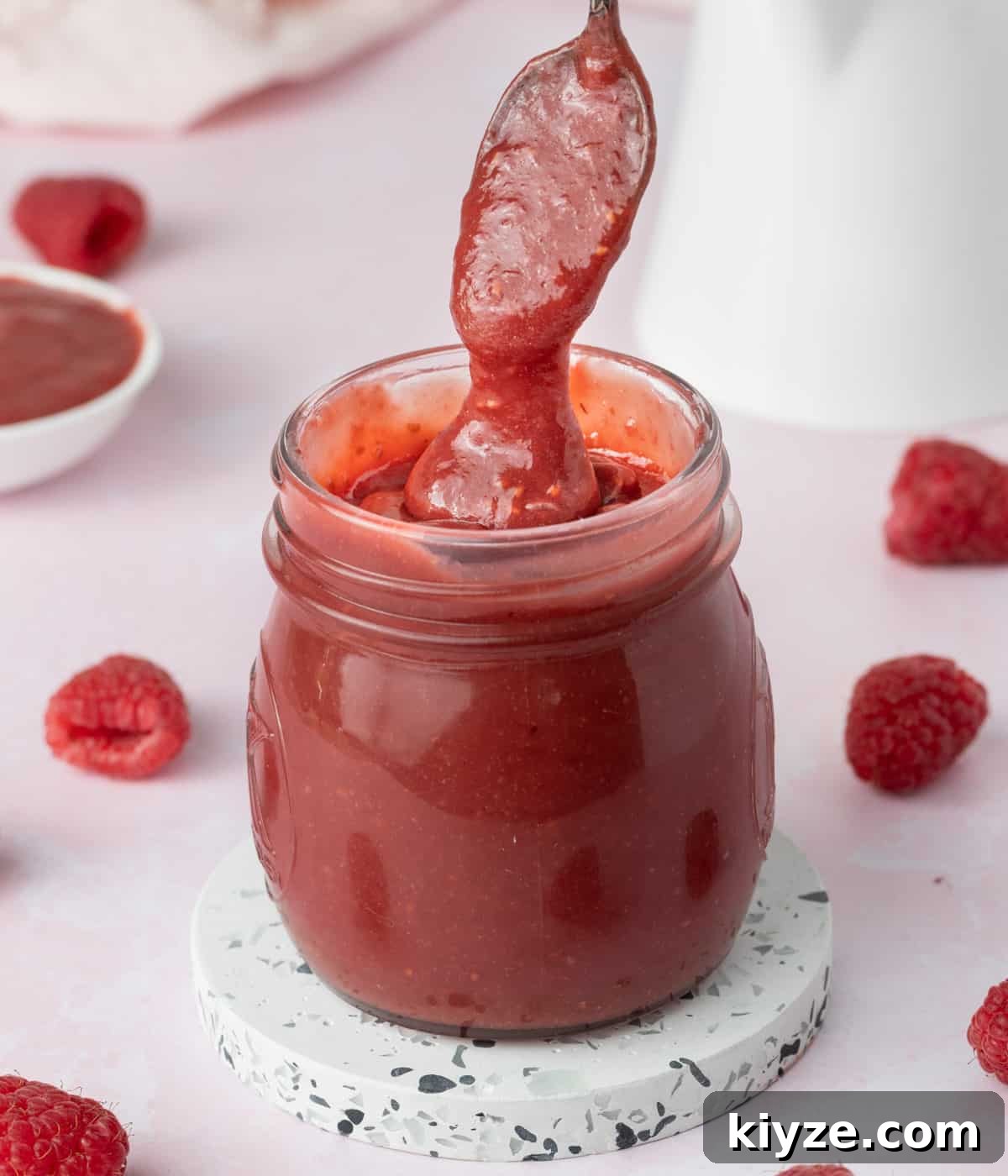 Curd dripping from a silver spoon into a jar.