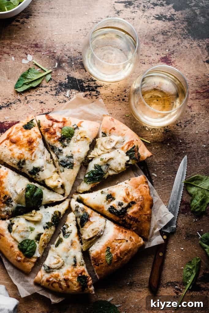 Deep-Dish Spinach and Artichoke Pizza Recipe 2 The sliced spinach artichoke pizza on a wooden surface.