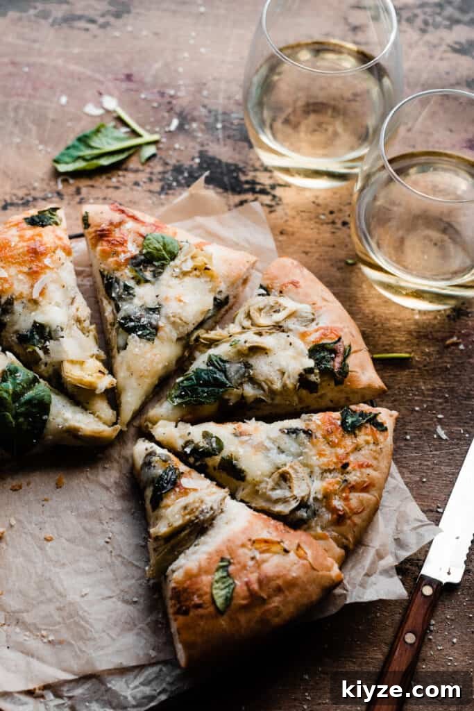 Deep-Dish Spinach and Artichoke Pizza Recipe 3 Sliced spinach artichoke pizza on a wooden background.