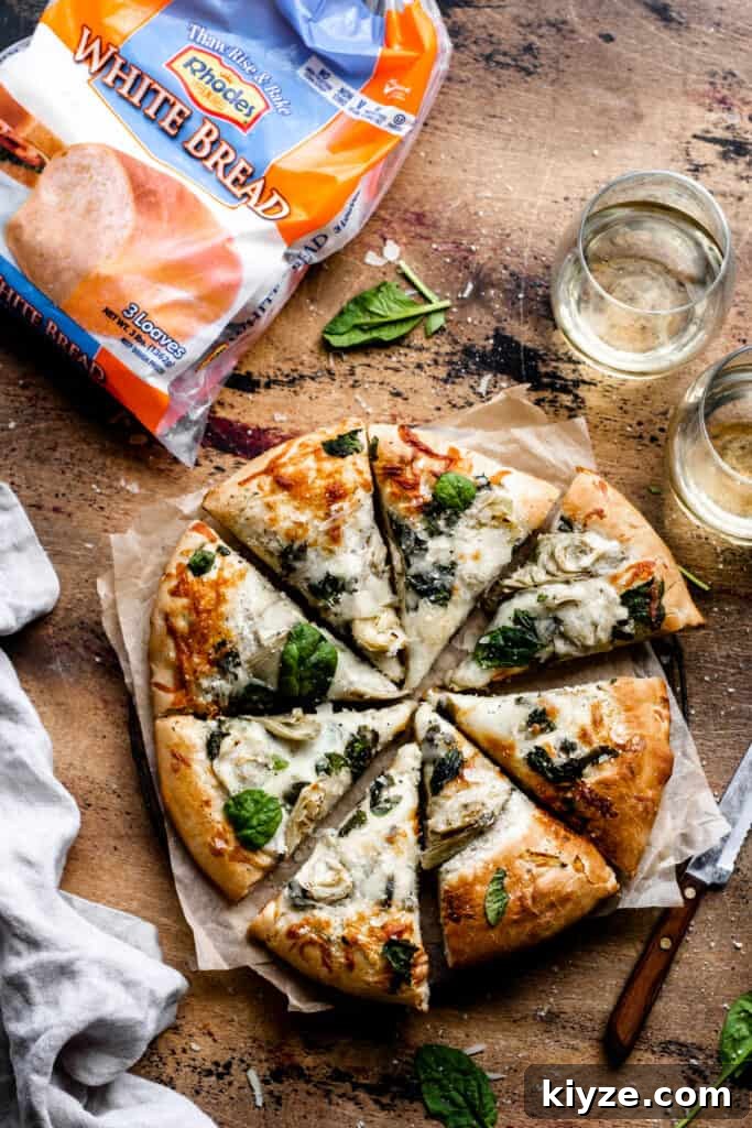 Deep-Dish Spinach and Artichoke Pizza Recipe 7 Sliced spinach artichoke pizza on a wooden surface.