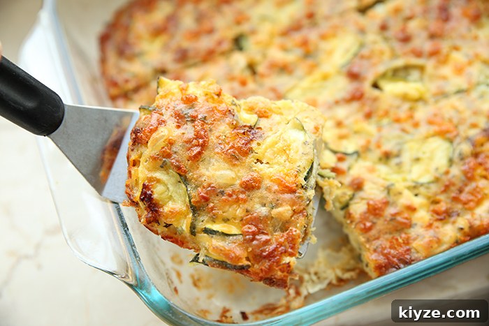 Zucchini pizza casserole in a glass 9x13 baking dish with a piece cut out of a corner held above with a serving spatula.