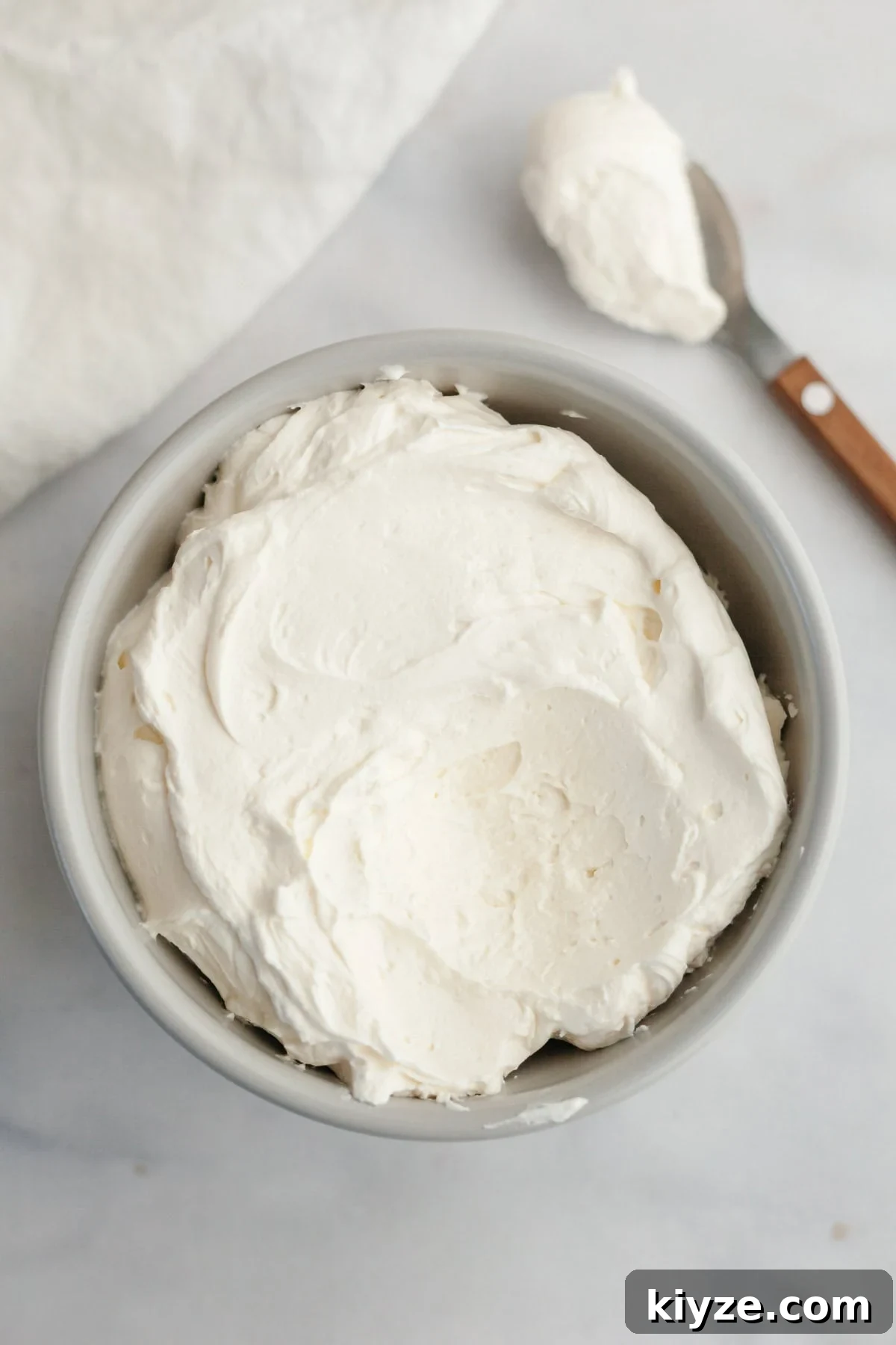 Mascarpone Whipped Cream Frosting Recipe — 5 Ingredients 2 A small grey bowl filled with mascarpone whipped cream frosting.