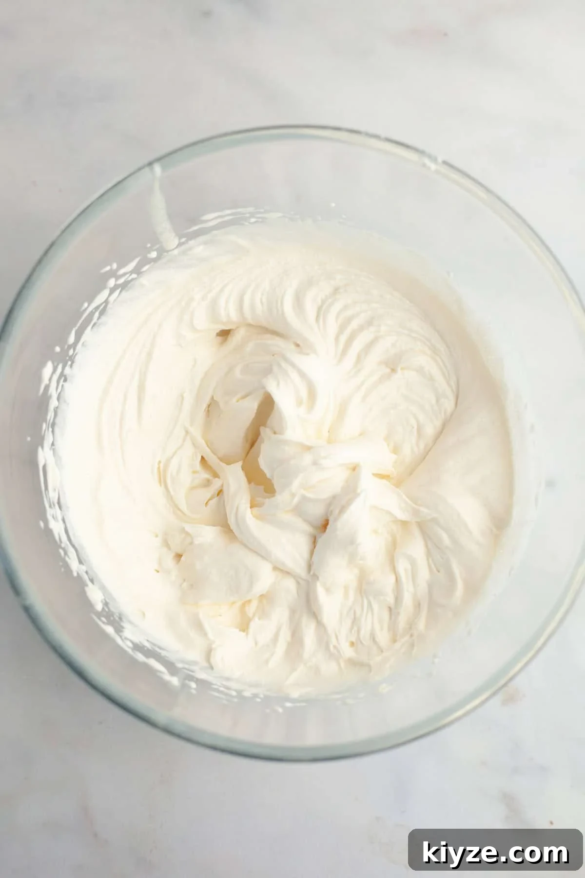 Mascarpone Whipped Cream Frosting Recipe — 5 Ingredients 5 A large glass bowl filled with mascarpone whipped cream frosting.