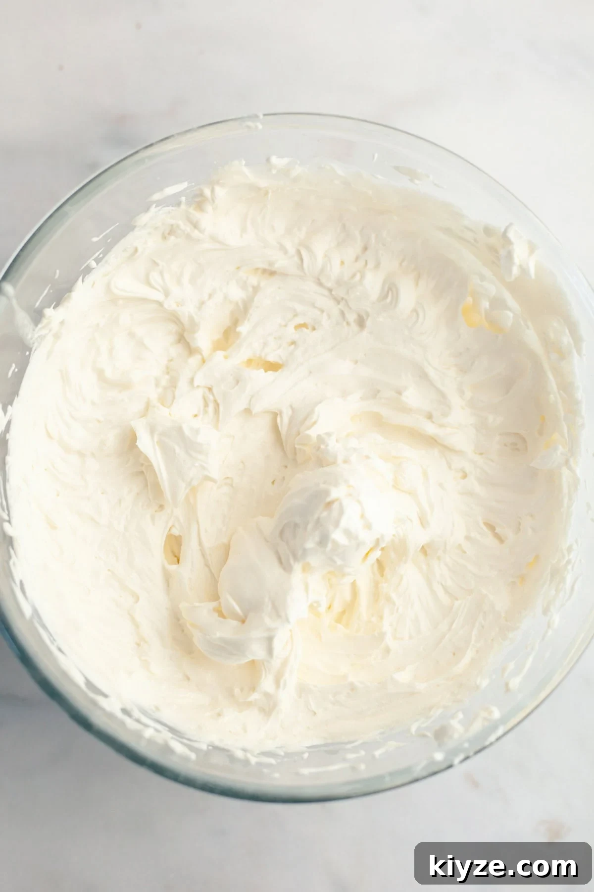 Mascarpone Whipped Cream Frosting Recipe — 5 Ingredients 7 A large glass bowl filled with mascarpone whipped cream frosting.