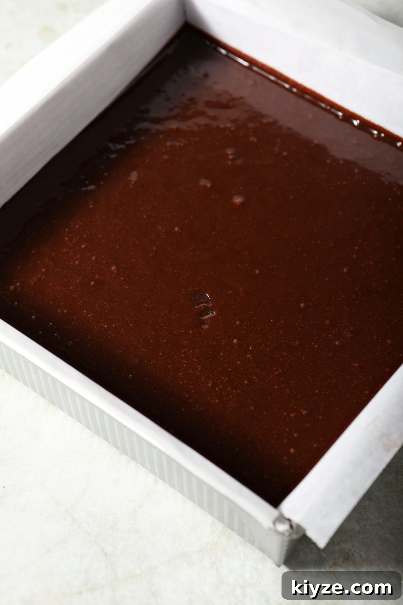 Decadent Guinness Chocolate Brownies: Rich Stout-Infused Recipe 5 Baked Guinness brownies in a tin on top of a wooden board on a green countertop next to a bowl of powdered sugar and beer bottle
