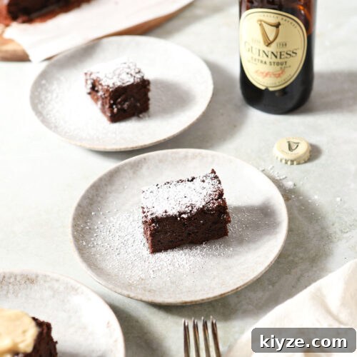 Decadent Guinness Chocolate Brownies: Rich Stout-Infused Recipe 8 Three brownies on grey plates on a light green surface with a cream-colored linen