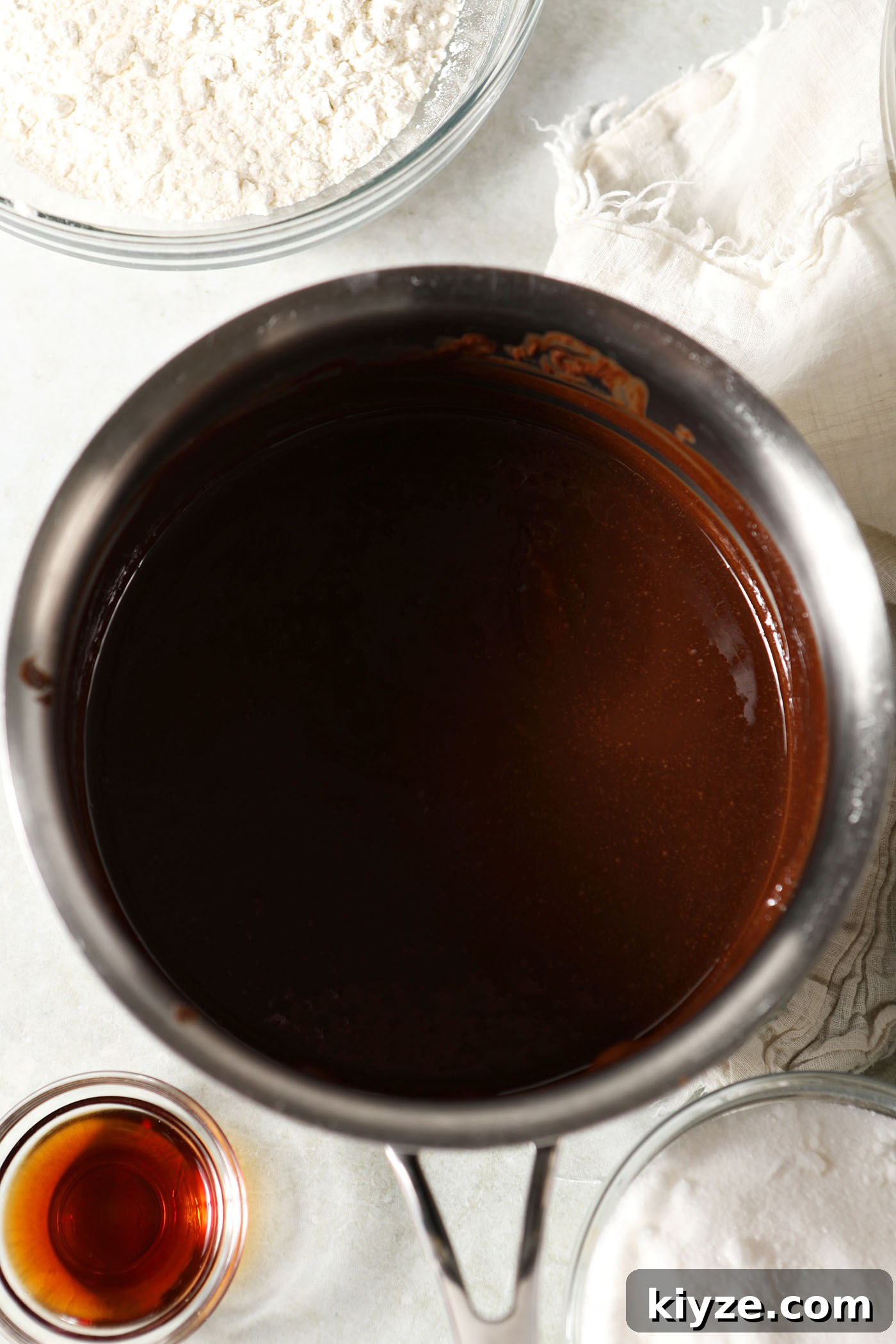 Decadent Guinness Chocolate Brownies: Rich Stout-Infused Recipe 4 Melted chocolate and butter in a saucepan on a green countertop surrounded by bowls of other ingredients