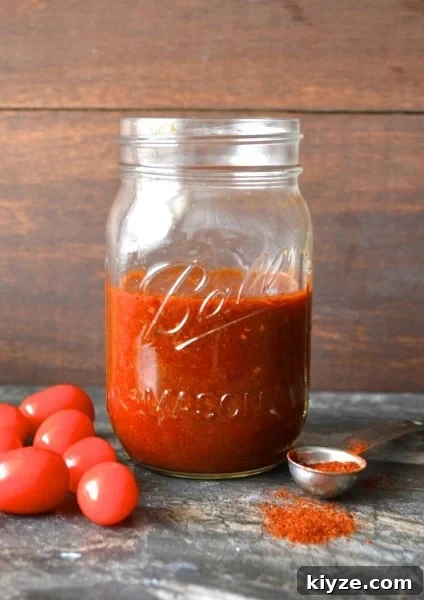 Authentic Homemade Enchilada Sauce Recipe for Rich Flavor 2 glass jar of homemade enchilada sauce with tomatoes on one side