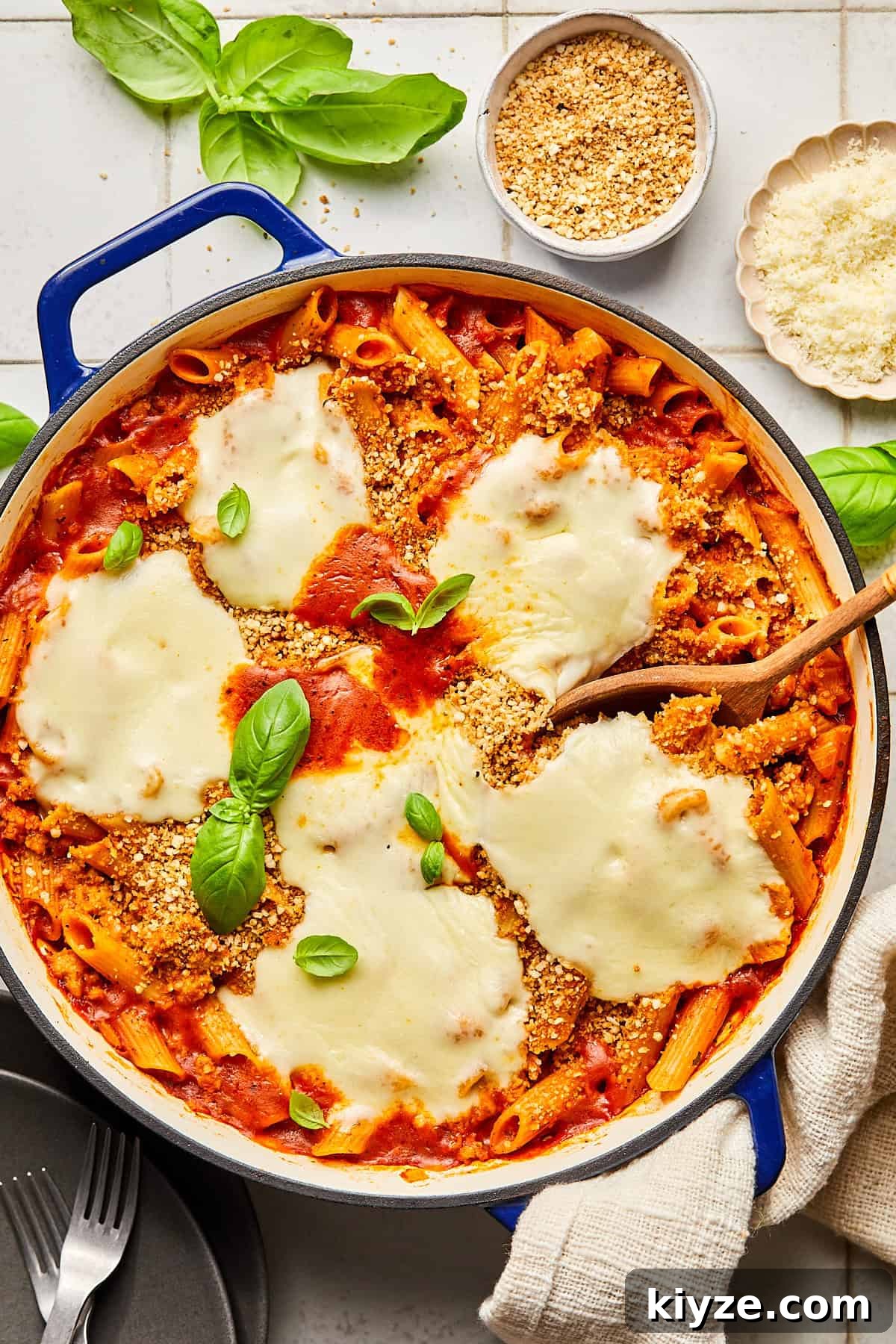 One-Pot Gluten-Free Chicken Parmesan Pasta Recipe 12 chicken parmesan pasta in a blue dutch oven surrounded by basil and ingredients