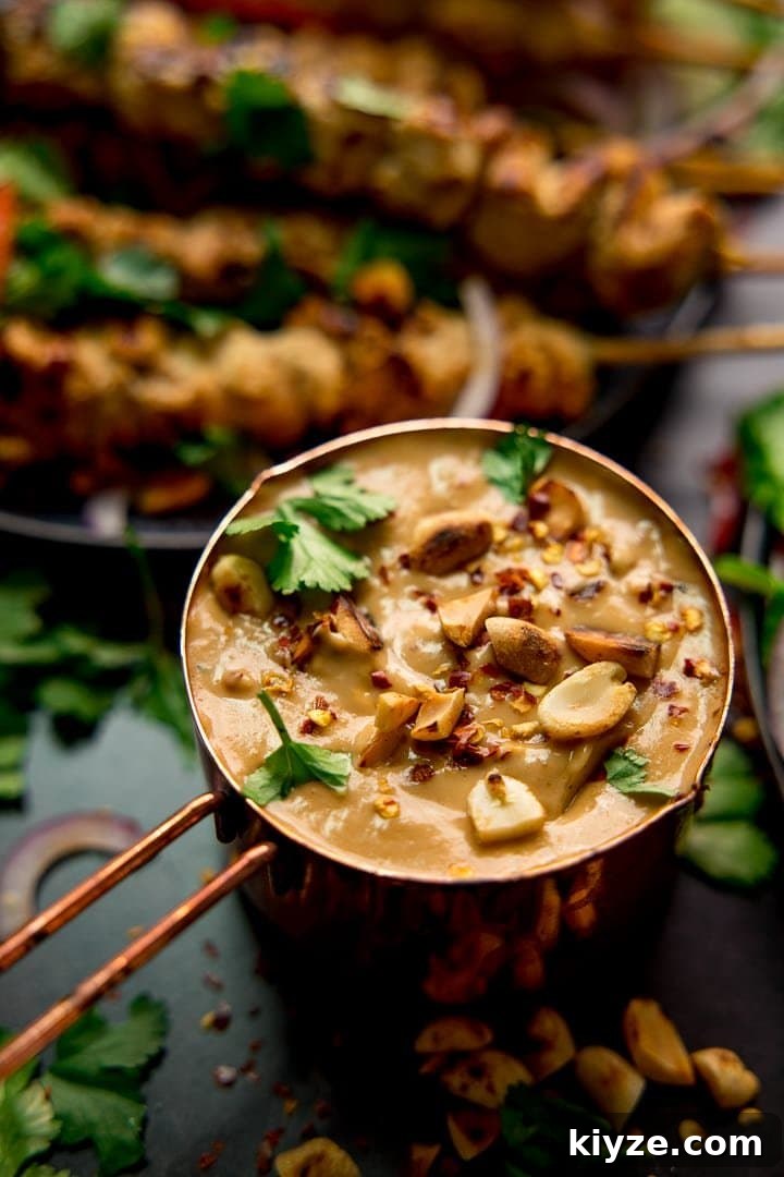 Homemade Satay Sauce Recipe for Grilled Chicken and Shrimp 6 Satay sauce in a small copper pan topped with peanuts and coriander. Chicken skewers in the background