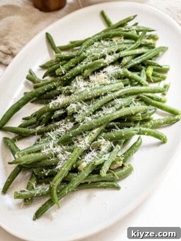 Sauteed green beans with garlic sprinkled with parmesan on a plate.
