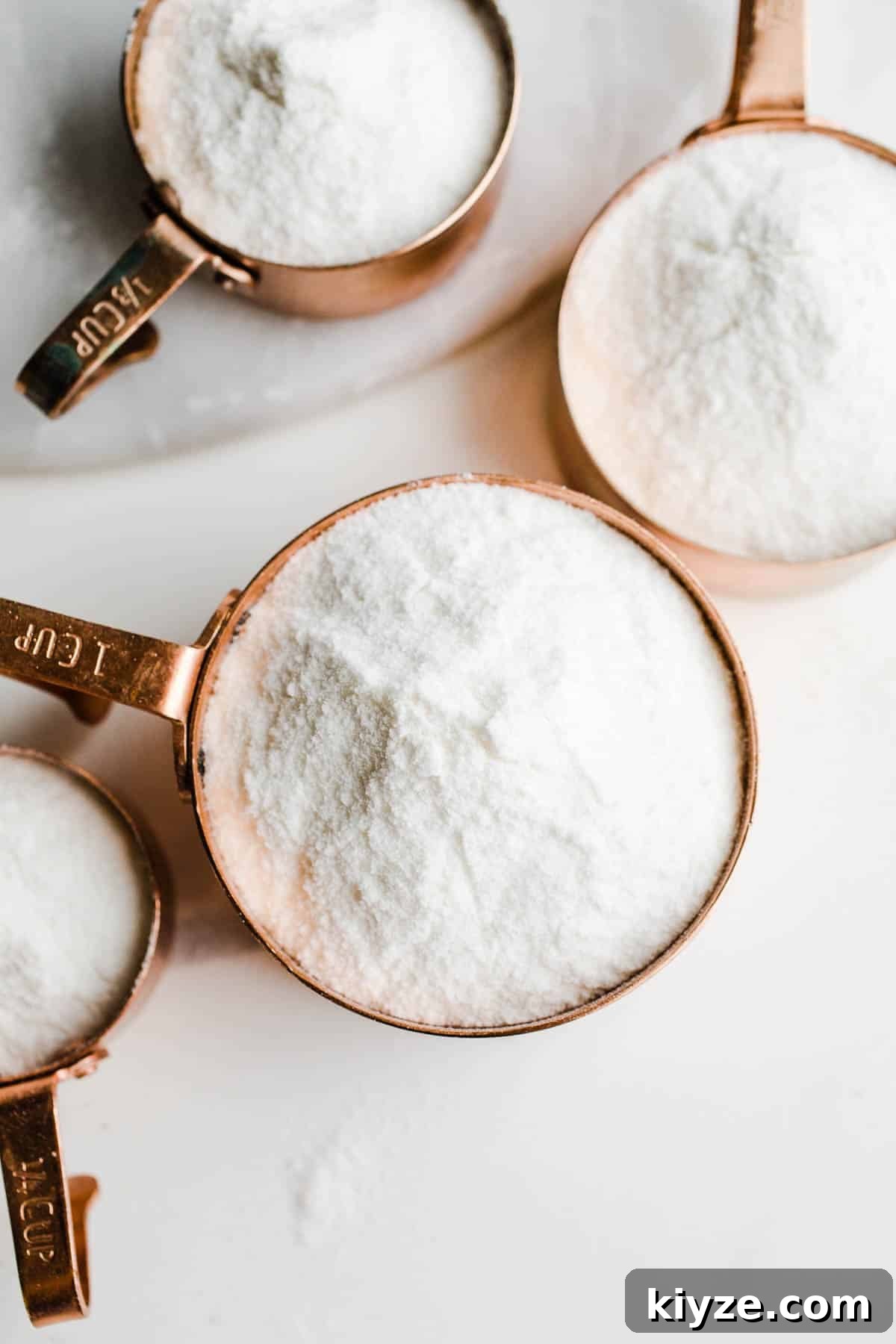 Measuring cups on a marble surface full of flour.
