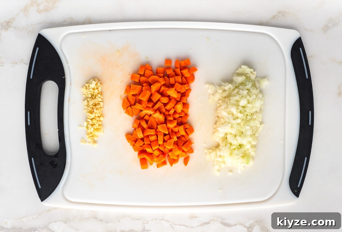 Traditional Lebanese Red Lentil Soup Recipe 4 Chopped garlic cloves, carrots and onion on cutting board.