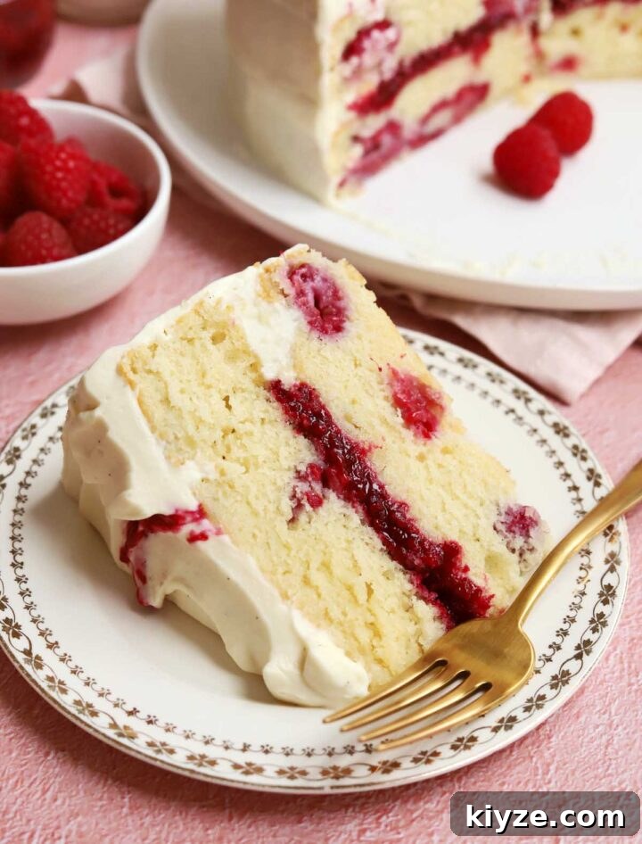 Decadent White Chocolate Raspberry Layer Cake Recipe 3 white chocolate raspberry cake slice on a plate