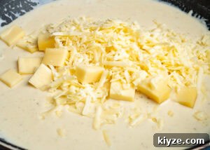 Cheesy Cauliflower and Broccoli Casserole Recipe 12 Gouda and mature cheddar cheese being added to the sauce in a frying pan