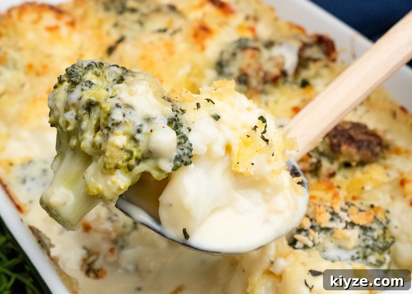 Cheesy Cauliflower and Broccoli Casserole Recipe 29 A piece of broccoli and cauliflower coated in melted cheese on a spoon