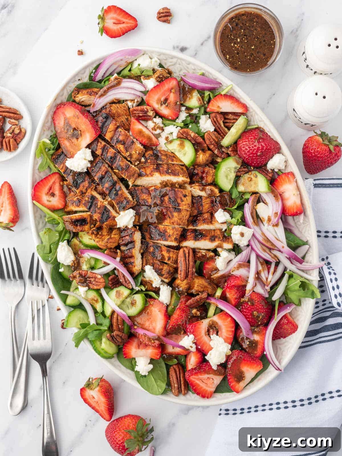 Grilled Chicken and Strawberry Salad with Balsamic Glaze 2 A large platter of spinach salad with strawberries and balsamic grilled chicken with several forks on the side.