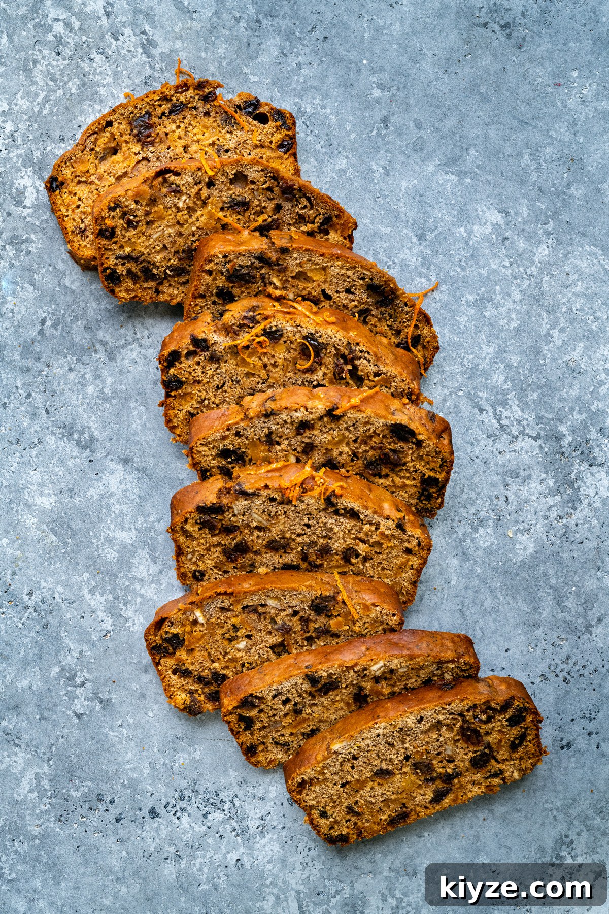 Tea-Infused Fruit Loaf Recipe for Afternoon Tea 4 sliced fruit loaf with mixed fruit laid out on a blue background