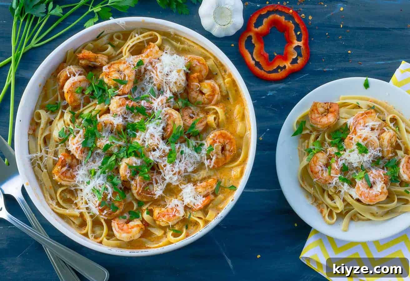 Cajun Shrimp Pasta with Roasted Red Pepper Sauce 5 Large serving bowl next to a small individual bowl of roasted red pepper pasta on grey background