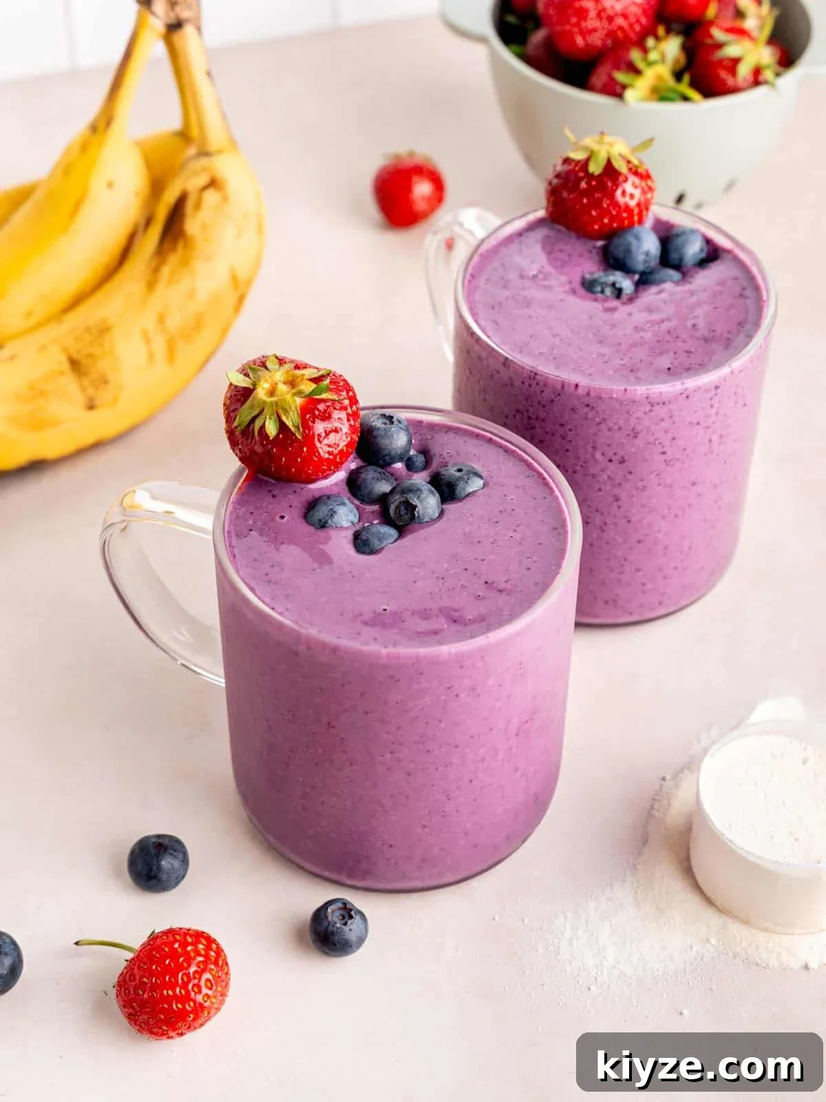 Creamy Banana and Berry Protein Smoothie Recipe 2 Two banana berry protein smoothies in clear glass cups.
