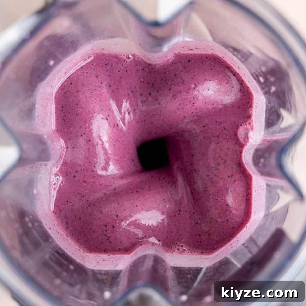 Creamy Banana and Berry Protein Smoothie Recipe 5 Top view of blending a fruit smoothie with protein powder in a Vitamix.