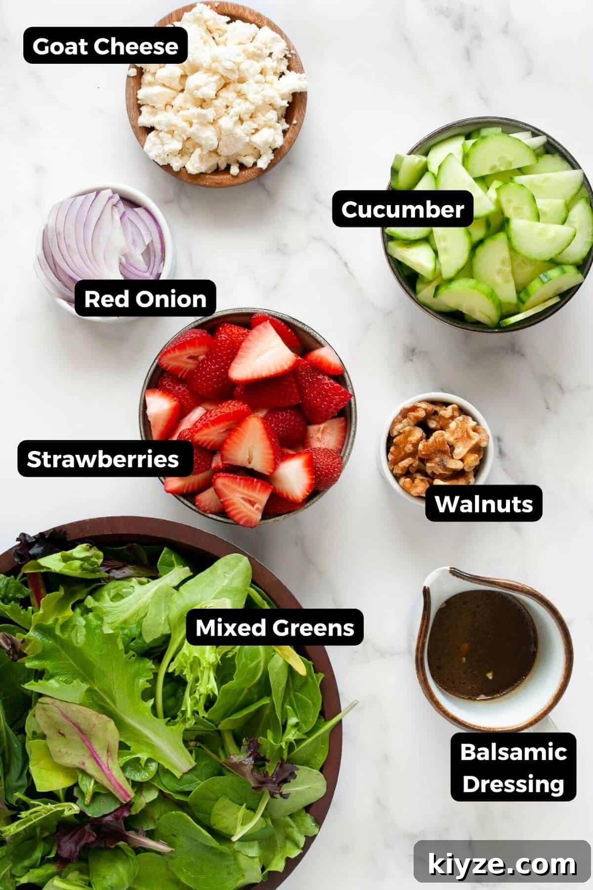 All ingredients in this strawberry goat cheese salad, including: mixed green with spinach, cucumbers, fresh strawberries, red onion, walnuts, goat cheese, and homemade balsamic dressing.