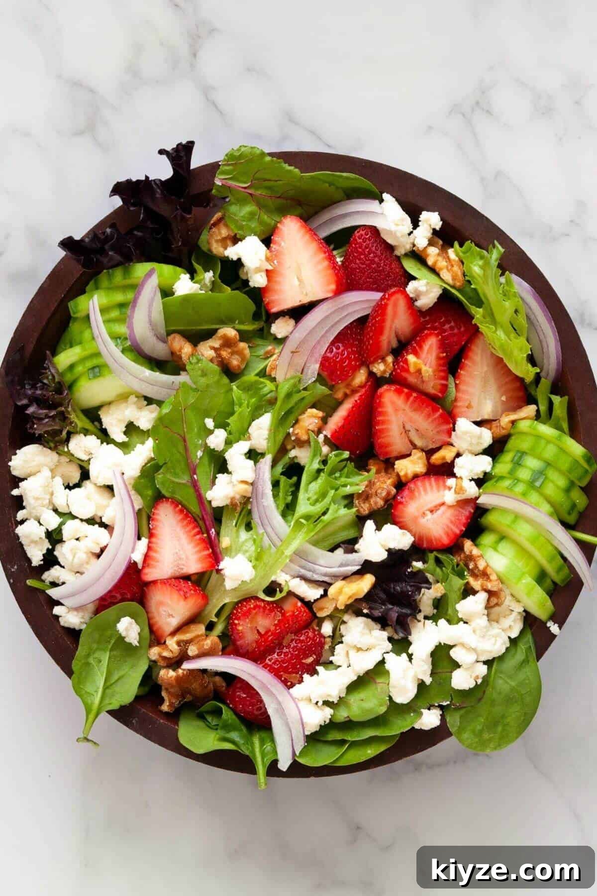 Undressed mixed green strawberry goat cheese salad in a bowl.
