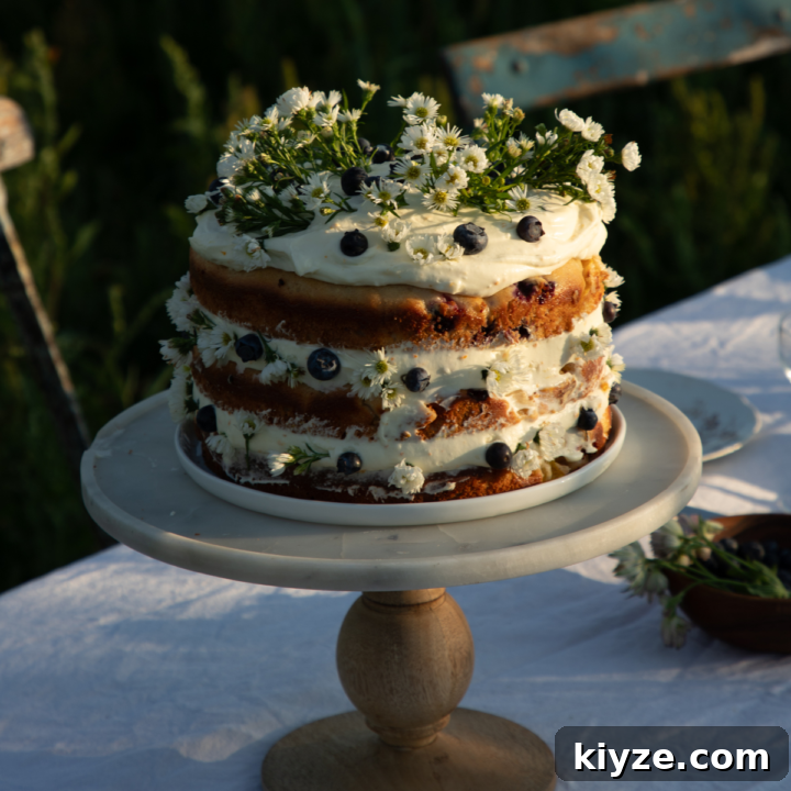 peach cake with orange zest whipped cream cheese frosting on a marble and wood cake stand